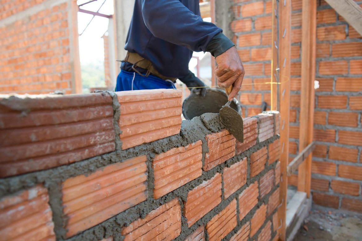 A man laying bricks on a wall.