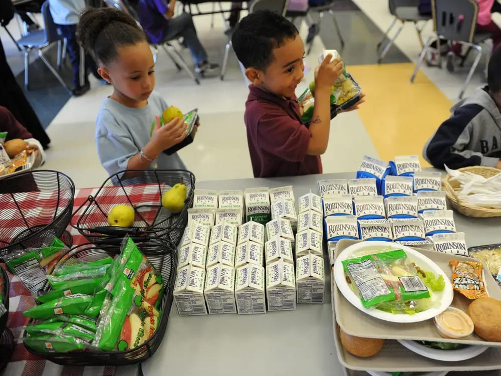 A couple of kids lining up for a school lunch.