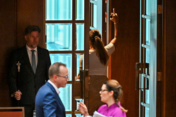 Lidia Thorpe leaving the Senate chamber with a middle finger in the air.